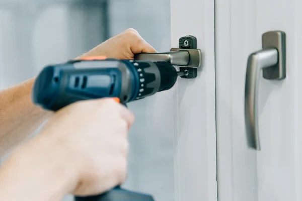 cropped shot of locksmith fixing window door lock and handle by electric drill
